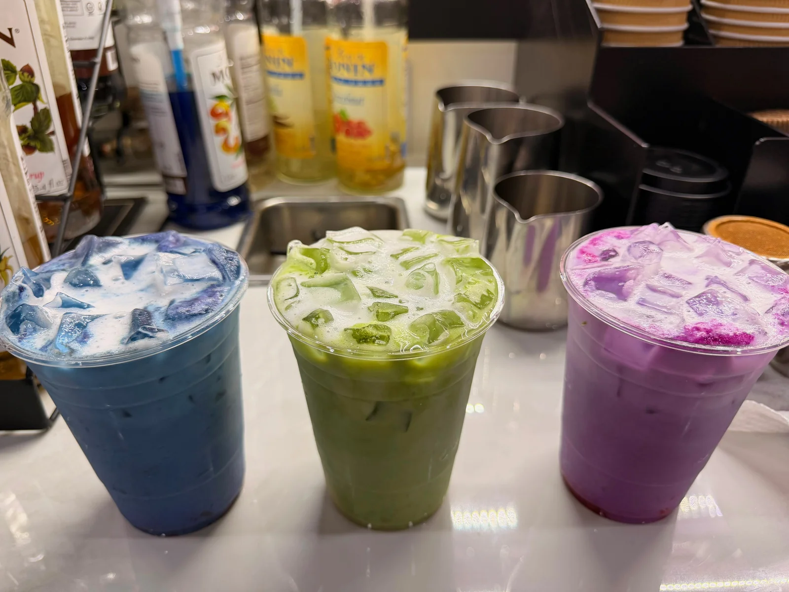 Three finished layered matcha drinks in blue, green and purple at Café Mia